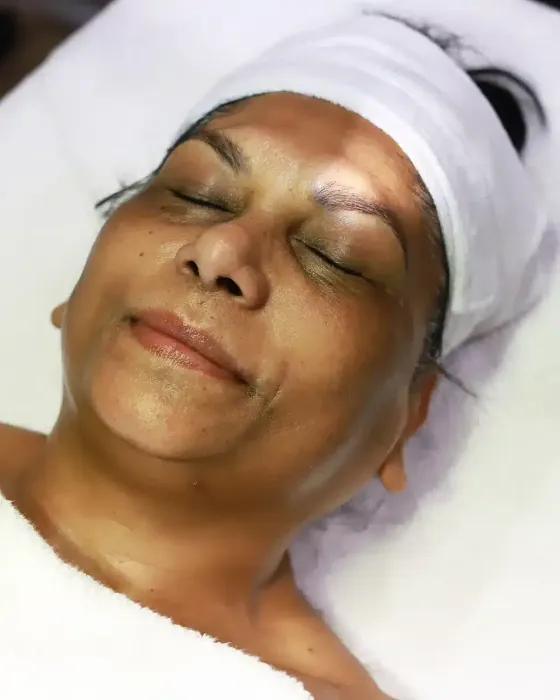 Een cliënte ligt met een masker op, hoofdband en witte handdoeken