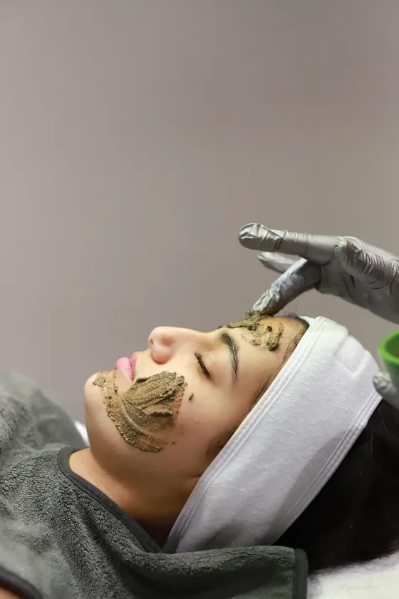 Een groen biopeelingmasker wordt met een handschoen aangebracht