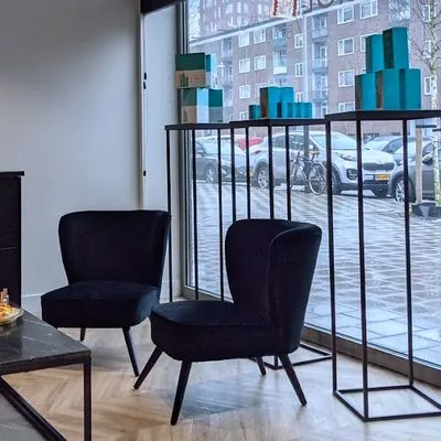 De lounge van Kapsalon Unique, waar de salon is gevestigd: zwarte fluwelen stoelen bij het raam